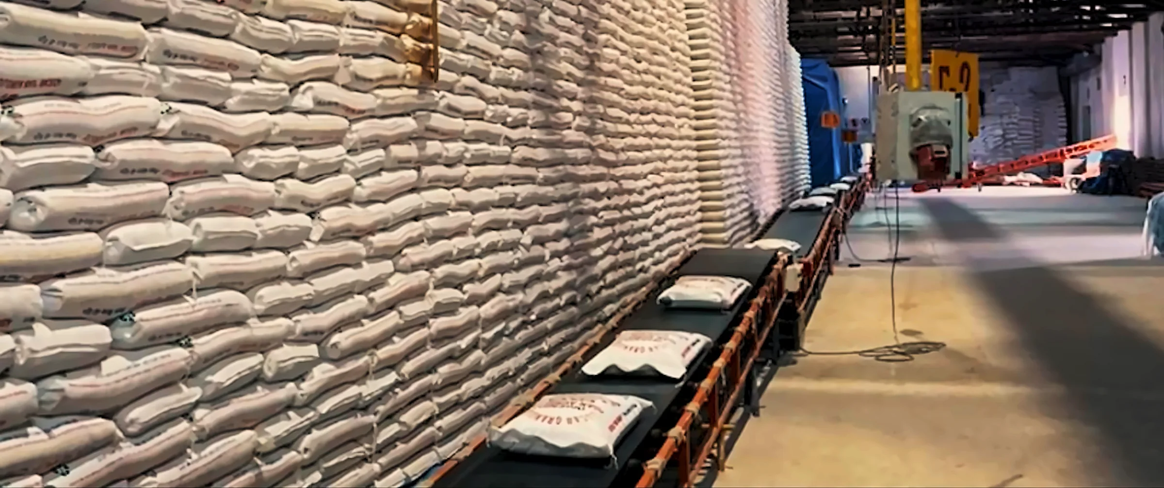 Almacén con sacos de producto y cinta transportadora